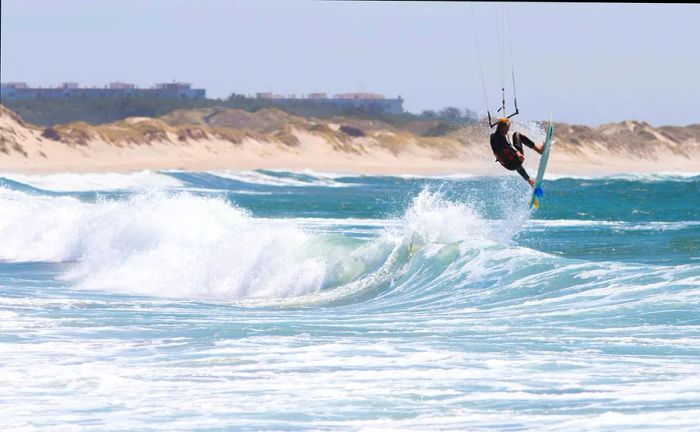 An athletic man kiteboarding on the waves at Cabedelo Beach, Viana do Castelo, Portugal