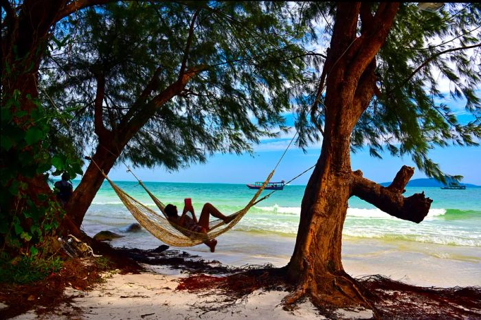 A woman relaxes in a hammock under the shade along the shores of Koh Rong.