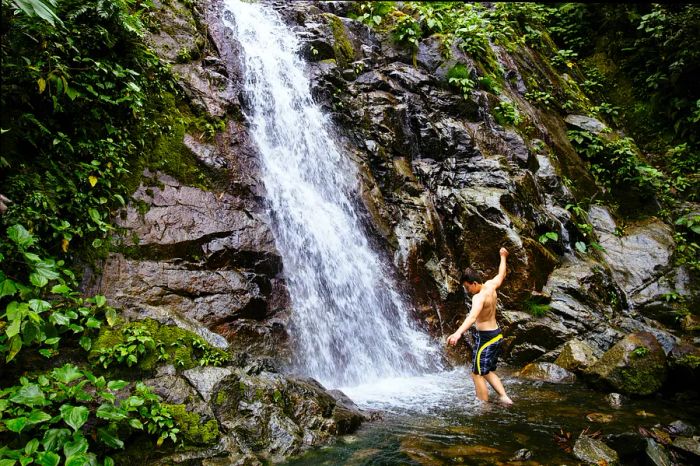 A young boy enjoys a refreshing splash under a waterfall