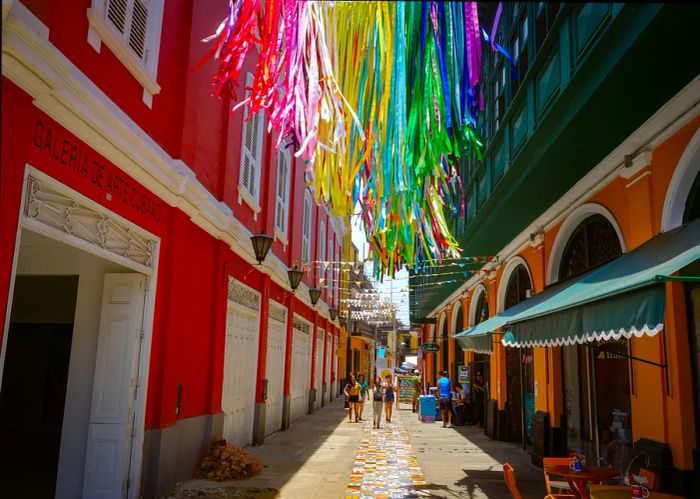 Pedestrians stroll through vibrant buildings adorned with street art in Callao Monumental.