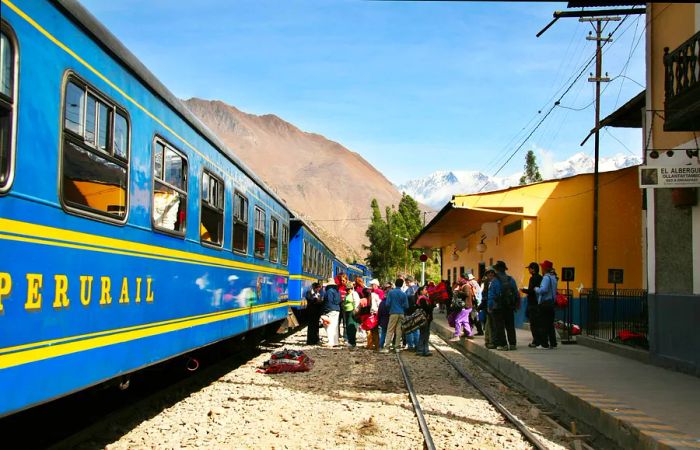 Passengers queue to board a blue train in the city of Machu Picchu, Peru.