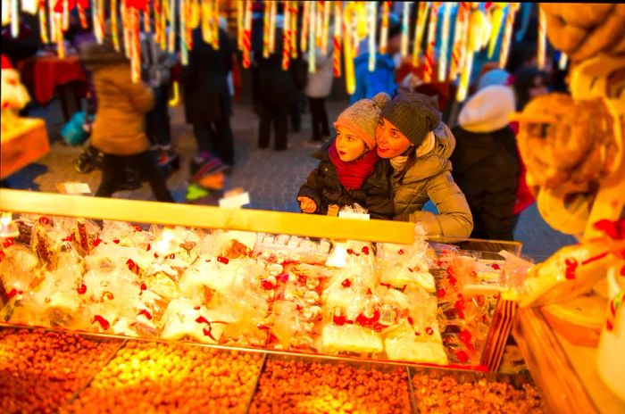 A child observes a sweet stall at a festive Christmas market.