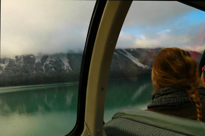 A woman gazes out the window of a train car, taking in the breathtaking scenery of Jasper National Park.