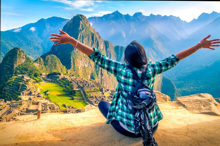 A female traveler gazing out over Machu Picchu with her arms wide open