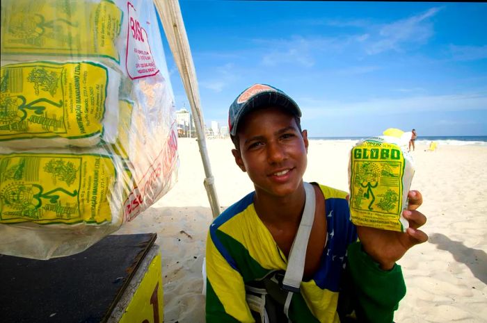 A young vendor selling Globo biscuits on the beach.