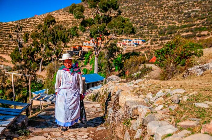 An Aymara woman strolls along a rocky path on Isla del Sol, situated on Lake Titicaca, Bolivia.