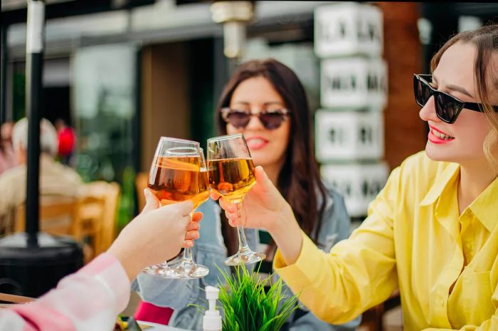 Women raise glasses of white wine while dining at a restaurant in Athens, Greece.