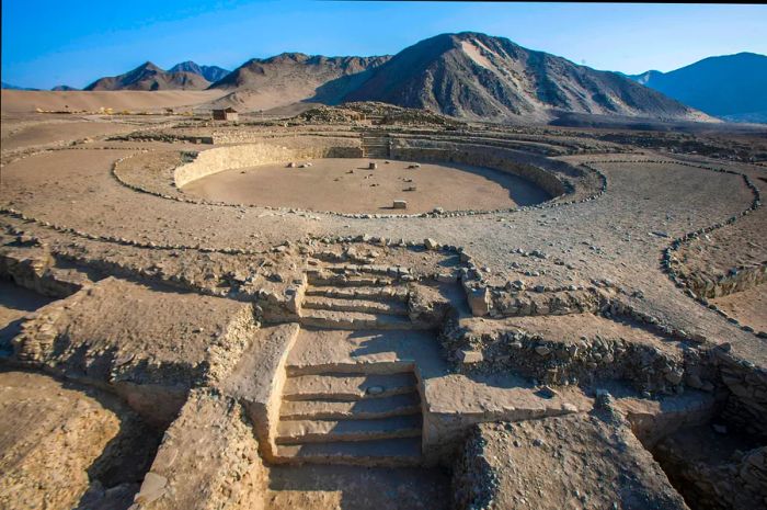 The ancient ruins of Caral, Peru, set against a backdrop of mountains