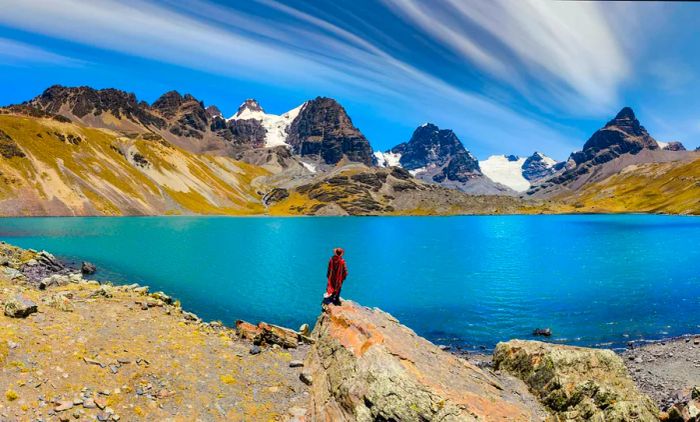 A traveler in a poncho gazes at the majestic Condoriri Peak in the Cordillera Real, Bolivia.