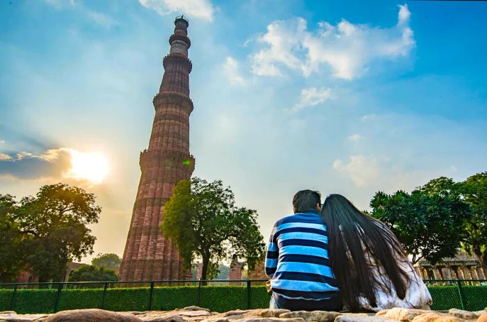 A couple enjoys the view of the Qutub Minar as the sun sets. The Qutub complex is situated in New Delhi, India.