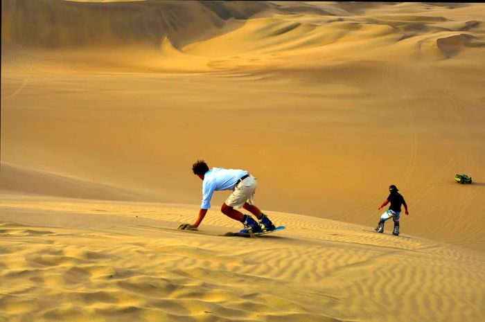 Individuals enjoying sandboarding in Peru