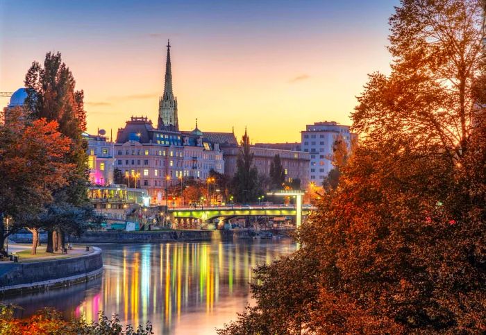 View of Vienna, with the evening city lights reflecting in the Danube canal and the iconic St. Stephen's Cathedral, captured from the Leopoldstadt district at sunset in late autumn.