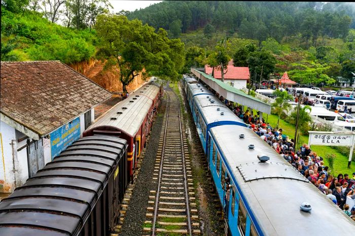 An aerial view of two trains at a busy station, with the right platform crowded with people