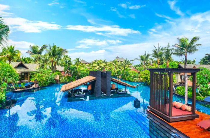 The lagoon pool at St Regis Bali, adorned with palm trees and sun loungers