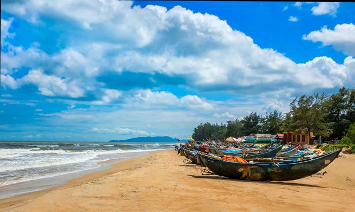 Fishing boats dot the golden sands of Ho Coc beach in Vietnam.