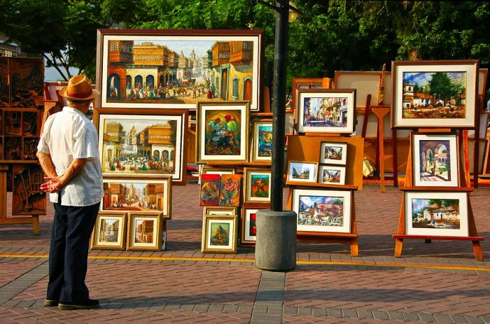 A man admires artwork displayed in a public park in Lima, Peru