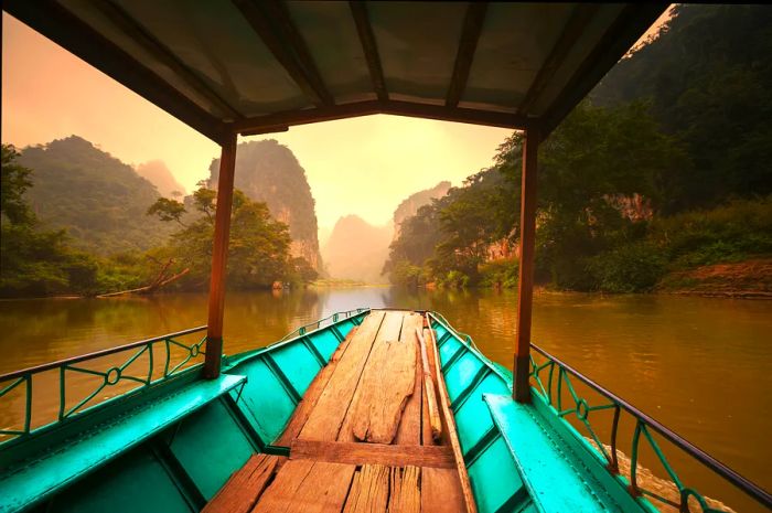 An empty boat gliding along a serene waterway in Ba Be National Park.