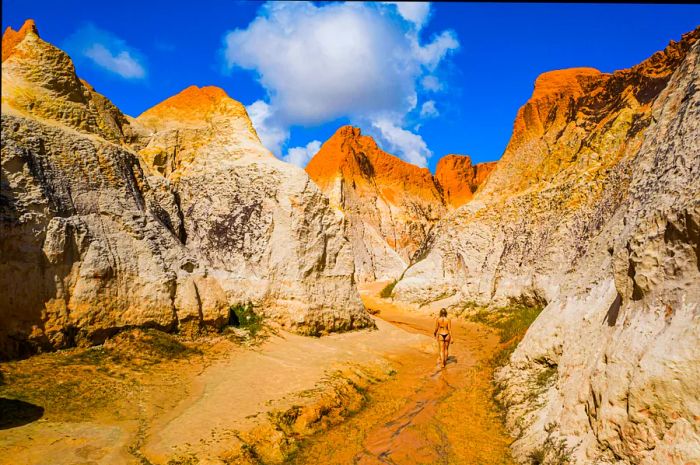 A woman strides into the ochre-hued dunes of Ceará, Brazil