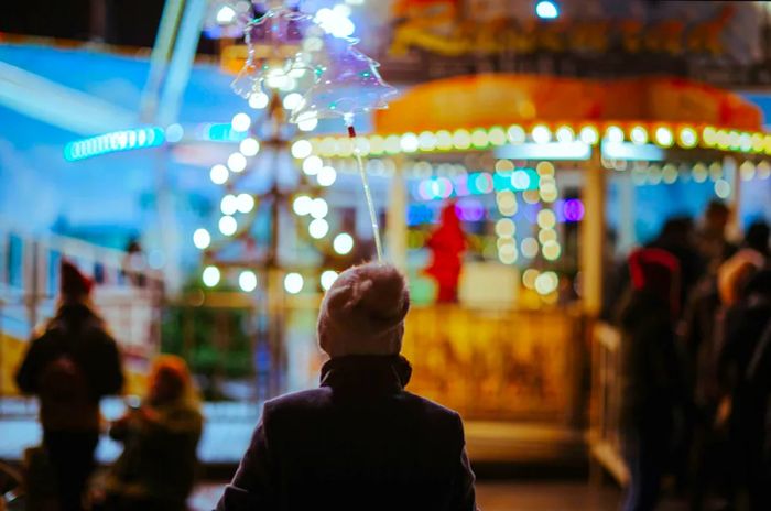 A young boy in a hat admires the dazzling Christmas lights at the night market in Dresden, Germany.