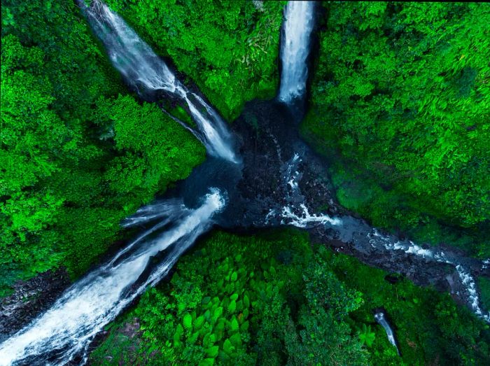 An aerial view of three waterfalls cascading through the forest into a single basin, Sekumpul, Bali