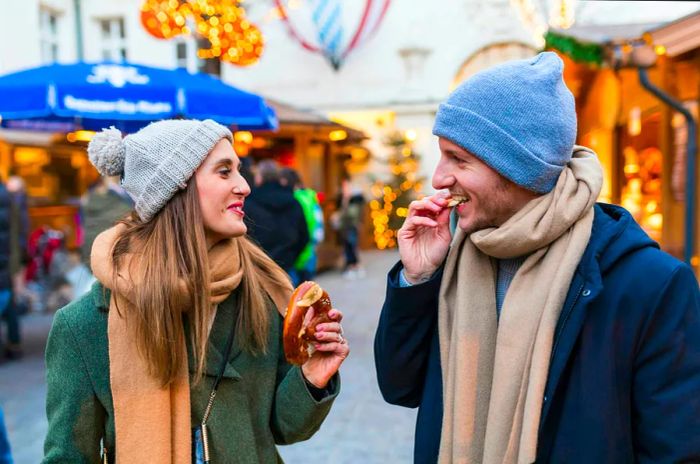 A couple enjoys pretzels at the Innsbruck Christmas market in Austria.