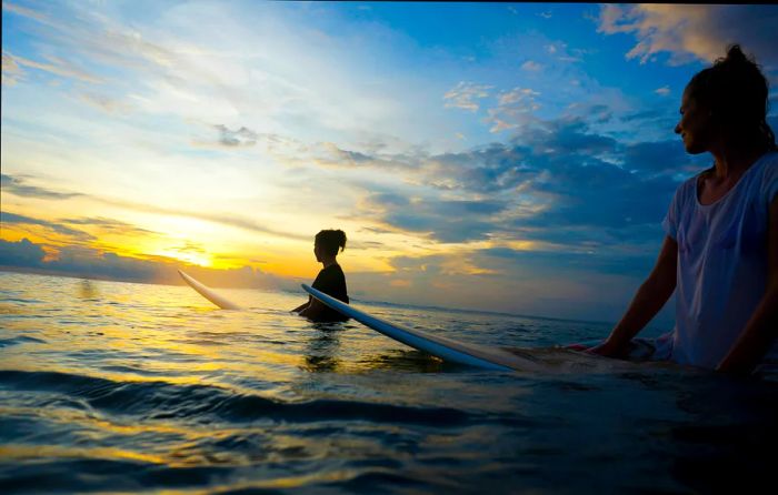 Indonesia, Bali, Canggu, two women surfing at sunset