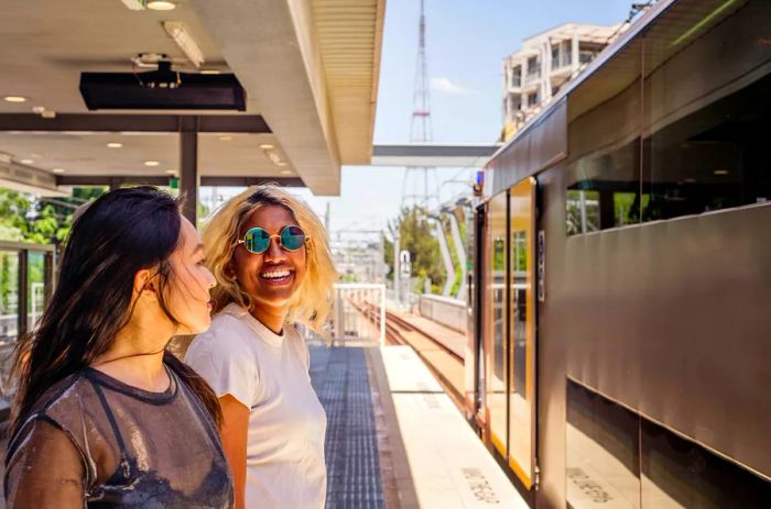 Two people share a laugh while waiting on a train platform