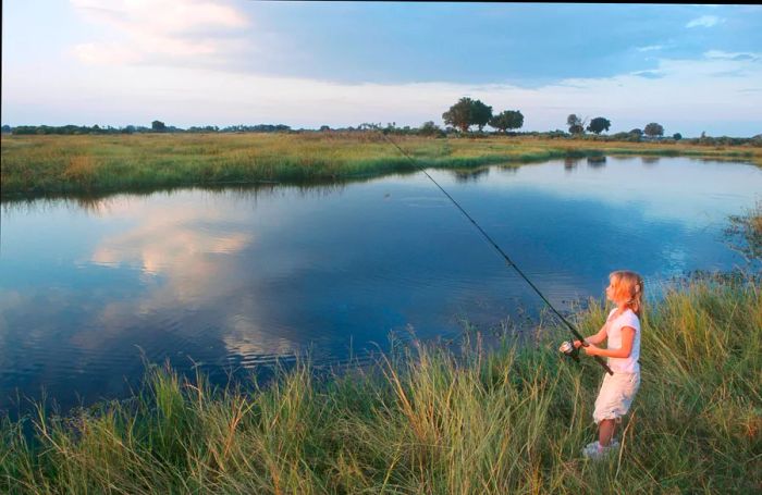 A young girl enjoys fishing in the Okavango Delta, Botswana