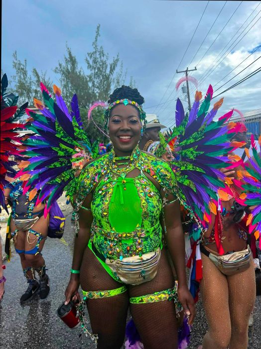 A woman beams with joy in a dazzling lime green Crop Over costume.