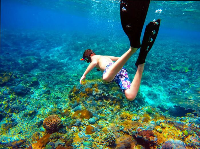 An underwater shot of a young boy snorkeling among the reefs off Nusa Penida