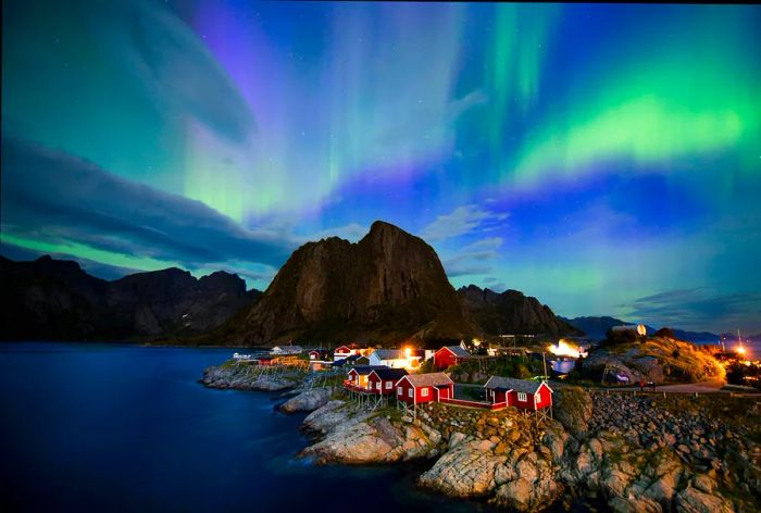 The northern lights (aurora borealis) light up the sky above Reinfjorden in Reine, Lofoten Islands, Norway