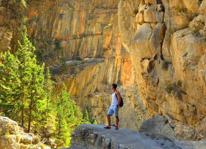 A young male hiker perched on a rock in the Samaria Gorge, Crete, Greece