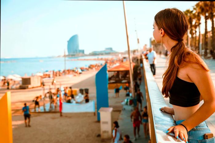 A teenage girl gazes out at the beach in Barcelona.