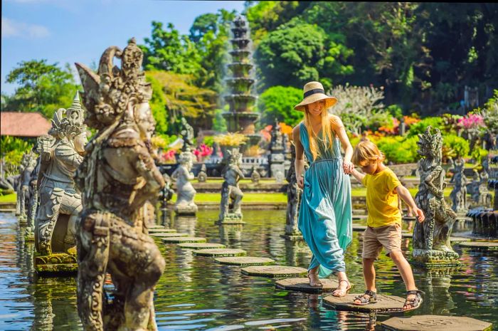 A mother and son explore the stepping stones at Taman Tirta Gangga, the Water Palace and park in Bali, Indonesia.