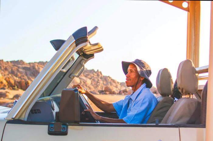 A cheerful driver sits in the front seat of a white car in Namibia