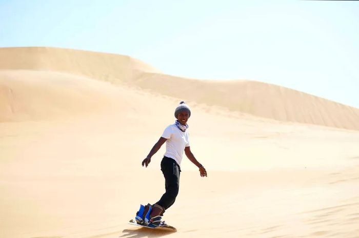 A young man sandboarding on the dunes