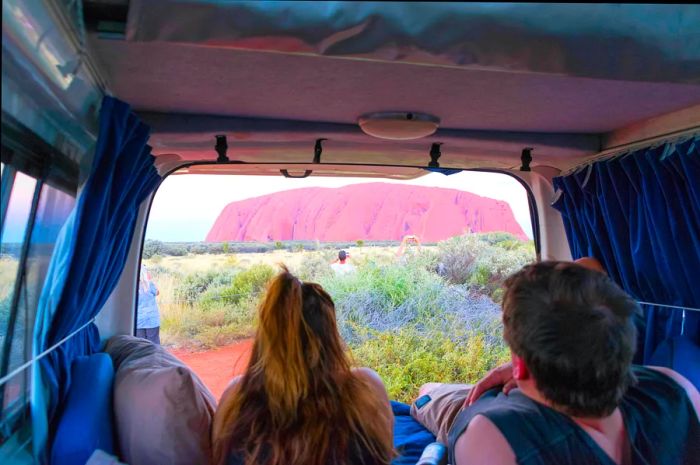 A view of Uluru at sunset from the back of a campervan.