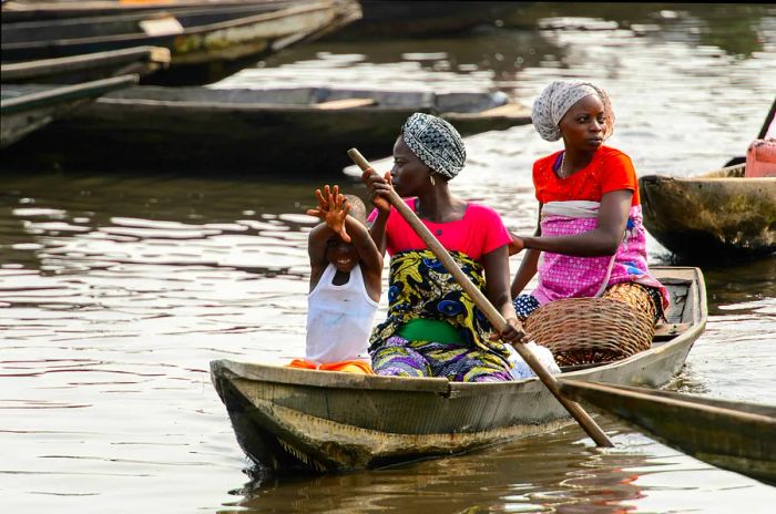 A Beninese family navigating Lake Nokoue in a wooden boat