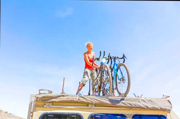 A young girl securing bicycles on the roof of a truck in Namibia