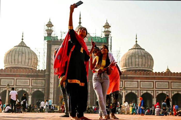 A woman with her children takes a selfie at Jama Masjid in Delhi, India.