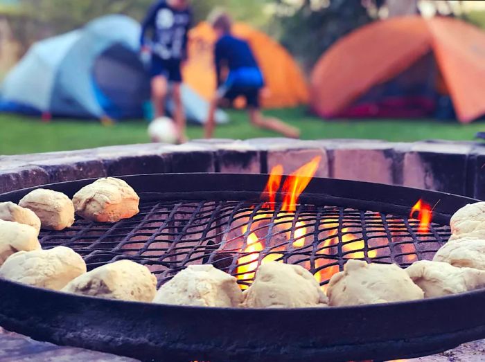 Two children kicking a football among tents at a campsite during a barbecue