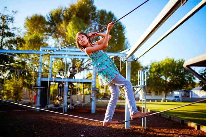 A young girl balances on a tightrope in a New Zealand playground