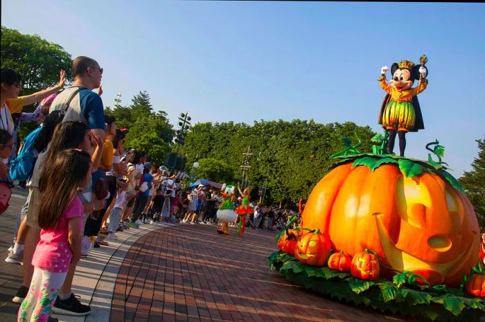 Tourists greet Mickey Mouse, who proudly perches atop a giant pumpkin during the Hong Kong Disneyland Halloween Parade.