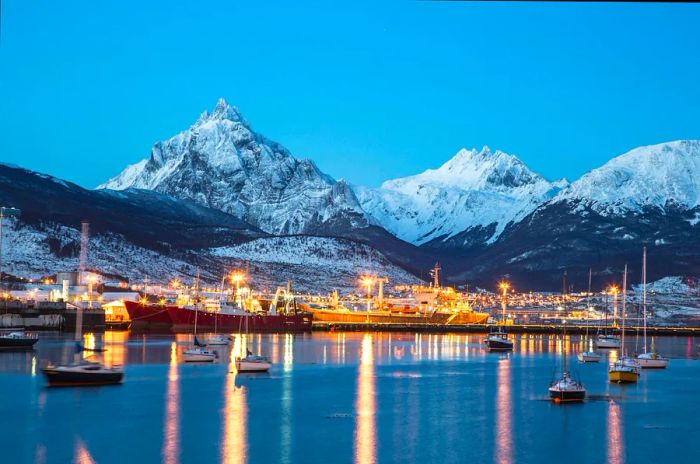 The port of Ushuaia illuminated at night, framed by snow-capped peaks, Ushuaia, Patagonia, Argentina, South America