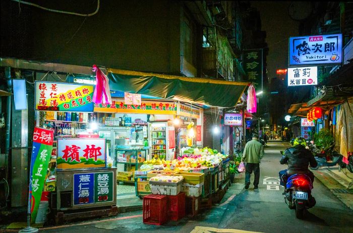 An illuminated alleyway at night featuring a Taipei back street convenience store in Taiwan