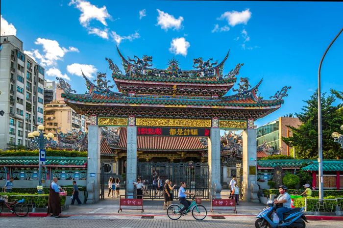 A cyclist rides past the ornate gate of Longshan Temple in Taipei, Taiwan