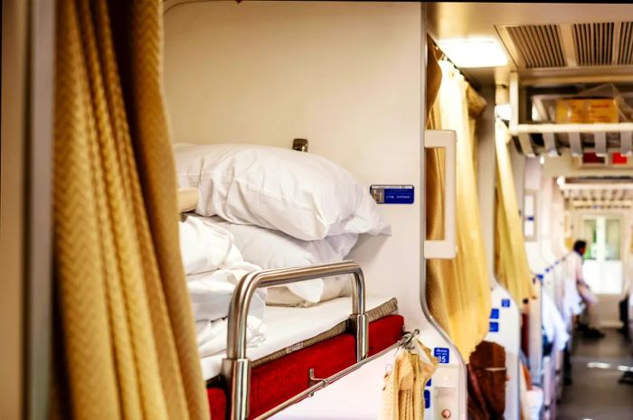 The interior of a second-class sleeper cabin on a modern Thai express train, complete with bedding for comfort.