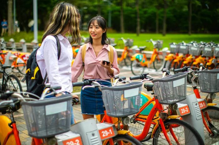 Two young women enjoying a bike rental together in a park in Taipei, Taiwan