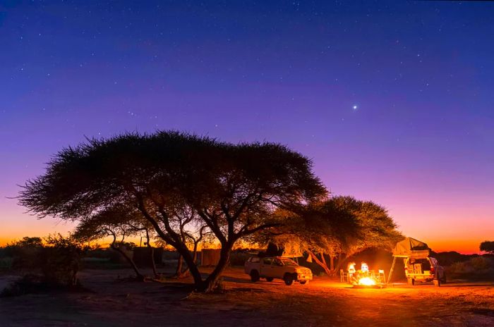 A campsite with a campfire under a starry sky in the heart of the Central Kalahari Game Reserve, Botswana