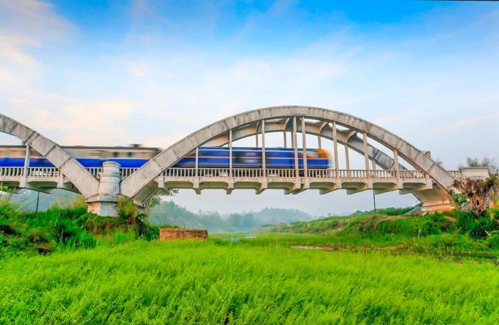 An old train traverses the Tha Chomphu Bridge in Lamphun Province, showcasing its charming white structure. Northern region.